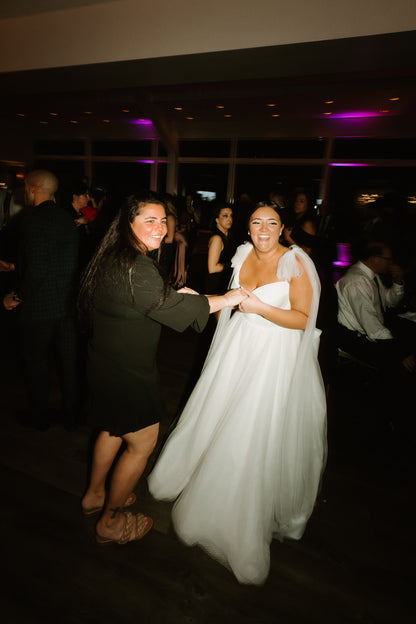 plus sized bride wearing tulle bow veils on shoulder as she dances