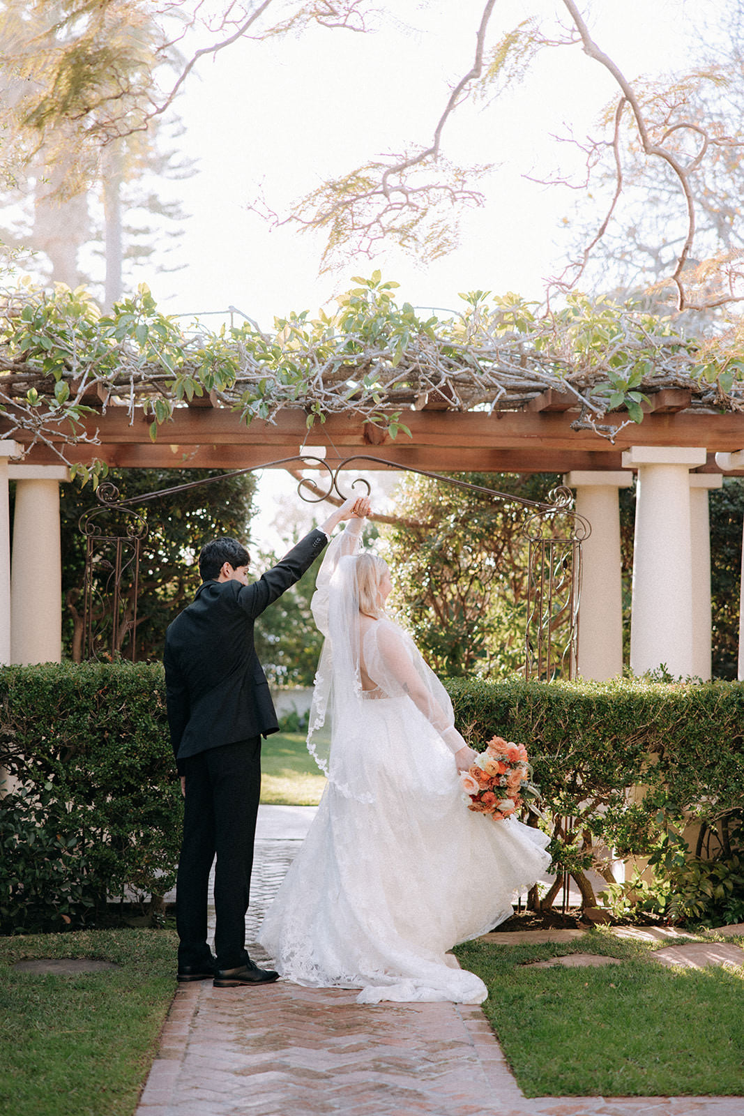 fingertip length bridal gown with leaves and vines as bride twirls with her groom