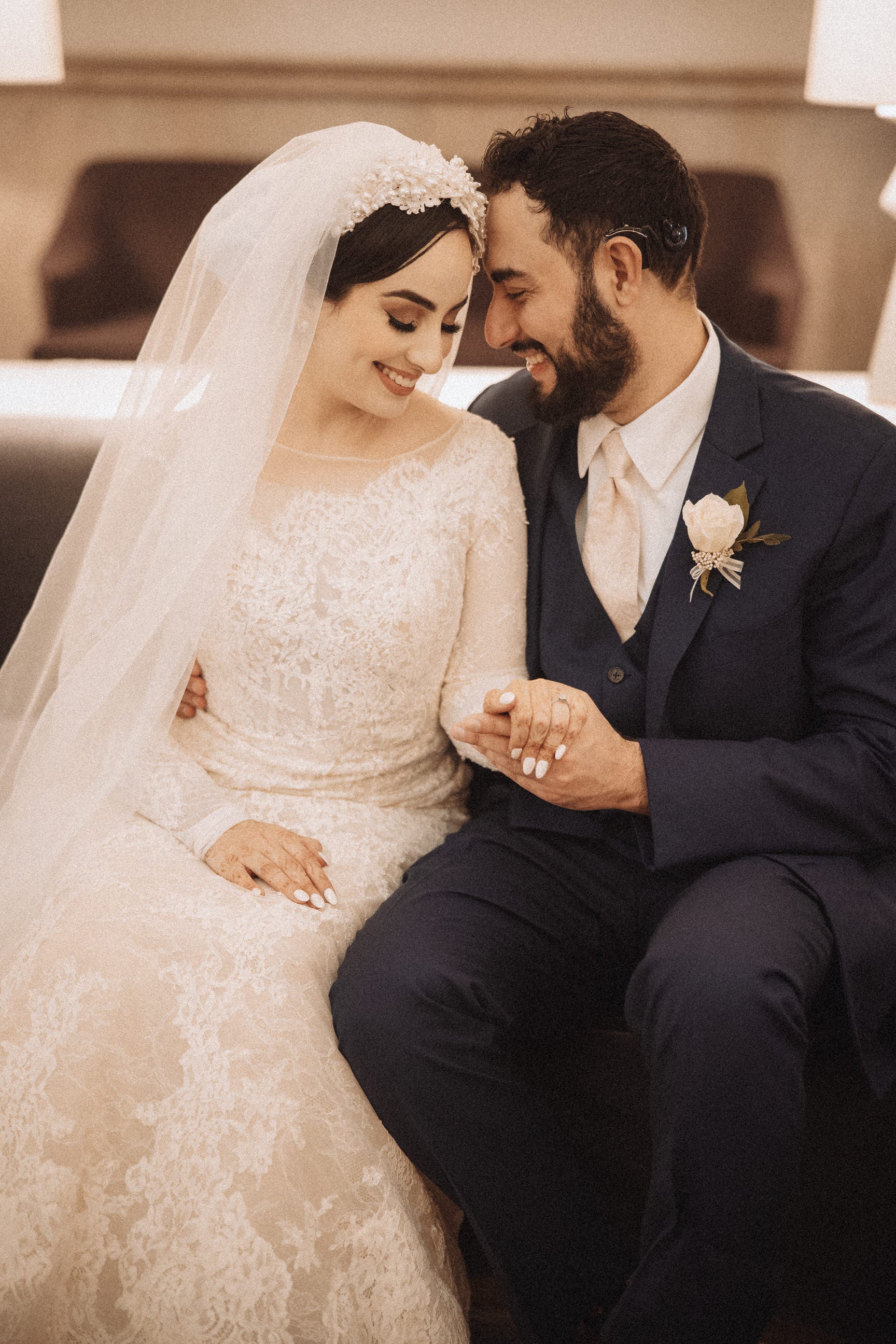 elegant bride wearing hair covering with pearl and lace and holding groom's hand